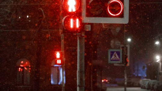 Traffic lights with red for transport and pedestrians during a snowfall at night