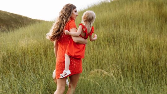 young beautiful mother and little daughter walking on nature on summer day vacation. Mom and